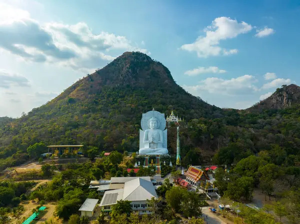 Görkemli bir Buda heykeli yemyeşil tepeler ve doğal ışık arasında meditasyon yapıyor. Bu huzurlu yer, kutsal mimarinin ve doğal güzelliğin uyumunu sergiliyor. dağ arkaplanı