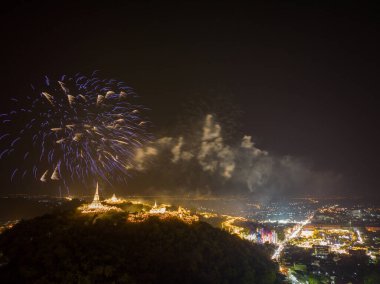 Havai fişeklerin göz kamaştırıcı gösterisi aydınlatılmış tepe sarayının üzerinde gece gökyüzünü aydınlatıyor. Bu coşkulu kutlama, karanlık gökyüzü ve Phetchaburi festivali havai fişekleriyle güzel bir tezat oluşturuyor..
