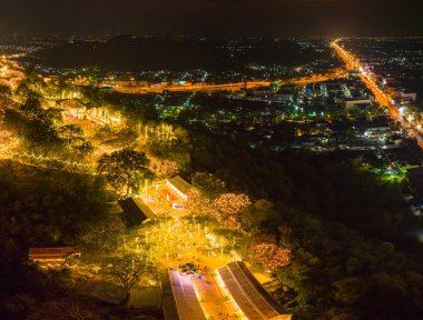 Havai fişeklerin göz kamaştırıcı gösterisi aydınlatılmış tepe sarayının üzerinde gece gökyüzünü aydınlatıyor. Bu coşkulu kutlama, karanlık gökyüzü ve Phetchaburi festivali havai fişekleriyle güzel bir tezat oluşturuyor..