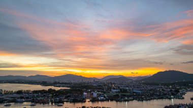Phuket 'teki büyük bir balıkçı limanının üzerindeki renkli gökyüzünün muhteşem panoramik görüntüsü. Bu liman büyük balıkçı tekneleri için bir merkez olarak önemlidir. Çarpıcı bir gün batımı gökyüzü suya yansıdı.