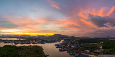 Durgun denizi yansıtan canlı sarı, pembe ve mor gün batımının nefes kesici görüntüsü. Bu sakin sahne Phuket balıkçılık limanında doğanın renklerinin güzelliğini yakalar. renkli bulut manzarası arkaplanı