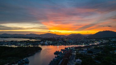 Durgun denizi yansıtan canlı sarı, pembe ve mor gün batımının nefes kesici görüntüsü. Bu sakin sahne Phuket balıkçılık limanında doğanın renklerinin güzelliğini yakalar. renkli bulut manzarası arkaplanı