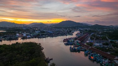 Phuket 'teki büyük bir balıkçı limanının üzerindeki renkli gökyüzünün muhteşem panoramik görüntüsü. Bu liman büyük balıkçı tekneleri için bir merkez olarak önemlidir. Çarpıcı bir gün batımı gökyüzü suya yansıdı.