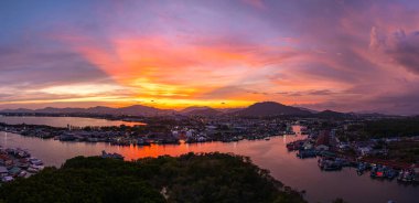 Phuket 'teki büyük bir balıkçı limanının üzerindeki renkli gökyüzünün muhteşem panoramik görüntüsü. Bu liman büyük balıkçı tekneleri için bir merkez olarak önemlidir. Çarpıcı bir gün batımı gökyüzü suya yansıdı.