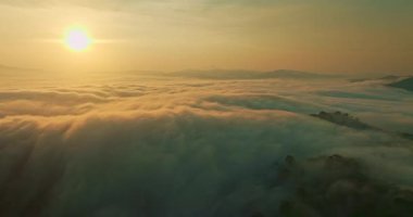 Bir şelaleye benzeyen sis denizi vadiden aşağı akıyor.