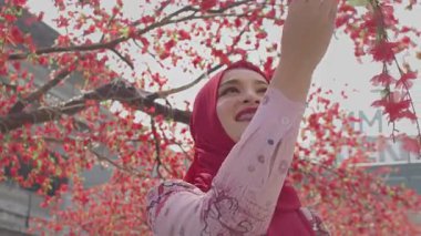 Şirin bayan Siam Meydanı 'nda sakura çiçekleriyle selfie çekiyor.