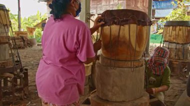 Tad davulunu yapan erkek ve kadın, ortasında delik olan büyük bir ahşap parçasından yapılmış çift taraflı bir davuldur..