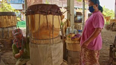 Tad davulunu yapan erkek ve kadın, ortasında delik olan büyük bir ahşap parçasından yapılmış çift taraflı bir davuldur..