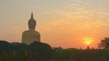 Pirinç tarlasındaki büyük Buda heykelinin üzerinde şaşırtıcı bir gün doğumu.