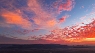 Nefes kesen bir gün doğumu, yemyeşil tarlaların ve karst dağlarının arasına kurulmuş, gökyüzünü dolduran canlı bulutlarla dolu küçük bir köyü aydınlatıyor. Kırsal yaşamın ahengi dramatik bir doğal oluşum oluşturdu.