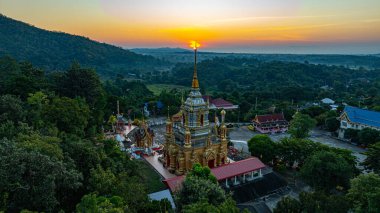 Gün doğumuyla birlikte Chiang Mai 'deki Mae Klang Şelalesi Tapınağı' nın hava görüntüsü sakin gökyüzünde sıcak renkler bırakıyor. Huzurlu ortam, tapınağın ve doğal manzaranın dingin güzelliğini vurguluyor..