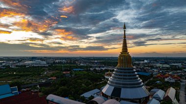 Hava Wat Ketmadi Sriwararam perspektifi bulutlu mavi gökyüzü altında şehir ve kırsal alanlarla çevrili büyüleyici bir Tayland tapınak kompleksi sergiliyor..