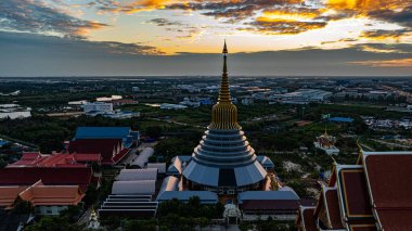 Hava Wat Ketmadi Sriwararam perspektifi bulutlu mavi gökyüzü altında şehir ve kırsal alanlarla çevrili büyüleyici bir Tayland tapınak kompleksi sergiliyor..