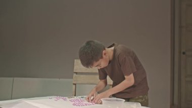 Asyalı çocuk pembe değerli taşları şekle sokuyor.