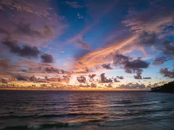 Pembe ve turuncu renkli canlı bir günbatımının çarpıcı bir sahnesi Karon plajı Phuket 'in üzerinde gökyüzünü aydınlatıyor. Doğanın inanılmaz ışığı bulutlu gökyüzü, harika gün batımı