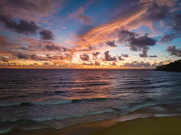 Pembe ve turuncu renkli canlı bir günbatımının çarpıcı bir sahnesi Karon plajı Phuket 'in üzerinde gökyüzünü aydınlatıyor. Doğanın inanılmaz ışığı bulutlu gökyüzü, harika gün batımı