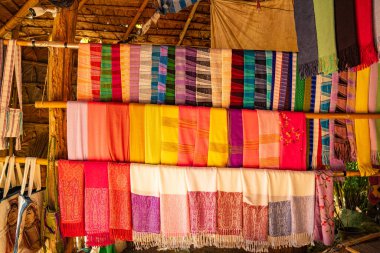 Karmaşık desenlere sahip kalın ve zengin renklerden oluşan geleneksel el dokuması kumaşların canlı bir gösterisi. Kuzeydeki dokuma geleneklerinin zanaatkarlığı ve kültürel mirası