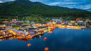 Baan Rak Tayland Köyü, gün batımında Çin tarzı mimaride göl kenarındaki ev ve restoranların renkli ışıklarla yansıması. Mae Hong Son 'da popüler bir turizm merkezi.