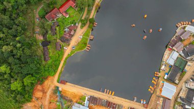Göl kenarındaki bir köyün havadan görünüşü, kırsal mimari, yemyeşil ve sakin sulara dağılmış teknelerin karışımı sergileniyor. Doğal güzellik ve insan yerleşiminin ahenkli bir karışımı.