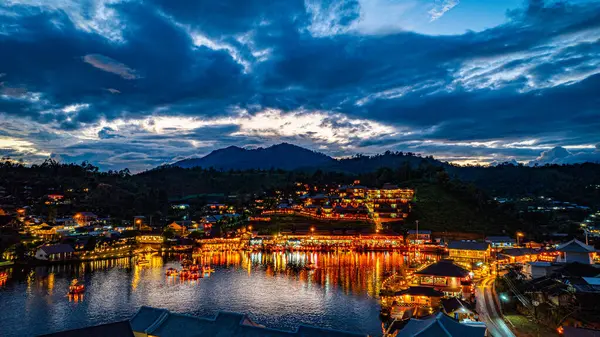 Baan Rak Tayland Köyü, gün batımında Çin tarzı mimaride göl kenarındaki ev ve restoranların renkli ışıklarla yansıması. Mae Hong Son 'da popüler bir turizm merkezi.