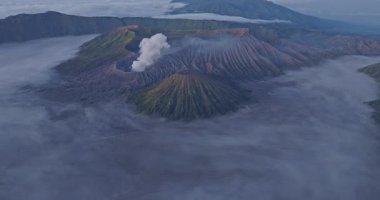 Bromo yanardağ kraterinin hava görüntüsü, beyaz duman yayılıyor.