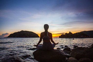 Sahilde yoga yapan bir kadın. 