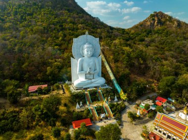 Görkemli bir Buda heykeli yemyeşil tepeler ve doğal ışık arasında meditasyon yapıyor. Bu huzurlu yer, kutsal mimarinin ve doğal güzelliğin uyumunu sergiliyor. dağ arkaplanı