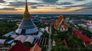 Hava Wat Ketmadi Sriwararam perspektifi bulutlu mavi gökyüzü altında şehir ve kırsal alanlarla çevrili büyüleyici bir Tayland tapınak kompleksi sergiliyor..