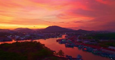 Kıyıdaki balıkçı limanının üzerinde canlı günbatımının hava manzarası.