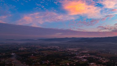 Nefes kesen bir gün doğumu, yemyeşil tarlaların ve karst dağlarının arasına kurulmuş, gökyüzünü dolduran canlı bulutlarla dolu küçük bir köyü aydınlatıyor. Kırsal yaşamın ahengi dramatik bir doğal oluşum oluşturdu.