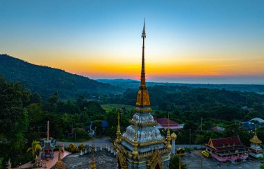Gün doğumuyla birlikte Chiang Mai 'deki Mae Klang Şelalesi Tapınağı' nın hava görüntüsü sakin gökyüzünde sıcak renkler bırakıyor. Huzurlu ortam, tapınağın ve doğal manzaranın dingin güzelliğini vurguluyor..