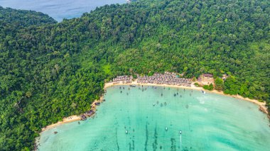 Morgan Köyü 'nün Surin Adası' ndaki doğal güzelliklere gizlenmiş havadan görüntüsü. Kıyı şeridi boyunca yemyeşil ormanlarla çevrili küçük kulübeler. Balıkçı tekneleri turkuaz sularda demirli..    