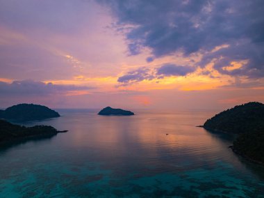 Surin Adaları 'ndaki Mai Ngam Plajı' ndaki tropikal bir sahil şeridinde gün batımının hava hiper yanılma görüntüsü. Gökyüzünün altın rengi suyu yansıtıyor, sakin ve resimsi bir deniz manzarası yaratıyor..