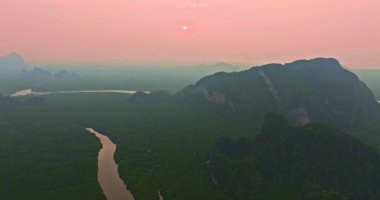 Güneşin doğuşunda yemyeşil dağların arasından süzülen sisli nehir.