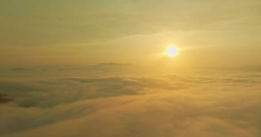 Altın gün doğumu, dağların üzerindeki sisli bulutları aydınlatıyor.