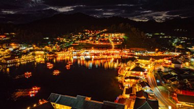 Baan Rak Tayland Köyü, gün batımında Çin tarzı mimaride göl kenarındaki ev ve restoranların renkli ışıklarla yansıması. Mae Hong Son 'da popüler bir turizm merkezi.
