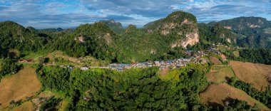 Güneşin erken saatlerinde sisli vadileri ve arkasında dramatik tepeleri olan bir dağ köyünün nefes kesici hava manzarası. Sahne, kırsal yaşamın dingin güzelliğini yakalıyor..  