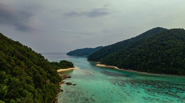 Bereketli yeşil tepeler, turkuaz tropik suyla buluşuyor.