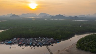 Bereketli mangrovlarla çevrili yüzen bir köyün nefes kesici hava manzarası. Güneş uzak kireçtaşı dağlarının ardında batıyor. Altın ışık sakin suları yansıtır. Bangpat Adası