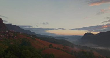 Güneş doğarken sisle kaplı yuvarlanan tepeler