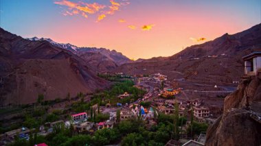 Renkli köy, gün batımında dramatik dağ manzarasının arasına yerleşmiş.