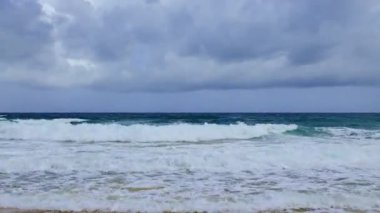 Bulutlu ufukta okyanus dalgaları çakılıyor.