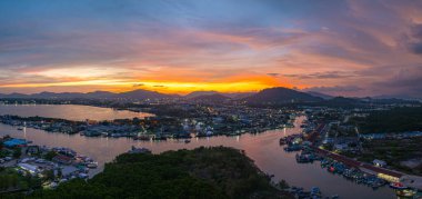 Durgun denizi yansıtan canlı sarı, pembe ve mor gün batımının nefes kesici görüntüsü. Bu sakin sahne Phuket balıkçılık limanında doğanın renklerinin güzelliğini yakalar. renkli bulut manzarası arkaplanı