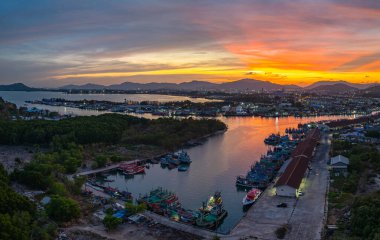 Phuket 'teki büyük bir balıkçı limanının üzerindeki renkli gökyüzünün muhteşem panoramik görüntüsü. Bu liman büyük balıkçı tekneleri için bir merkez olarak önemlidir. Çarpıcı bir gün batımı gökyüzü suya yansıdı.