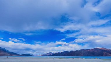 Uzak dağ gölünün üzerindeki geniş mavi gökyüzü