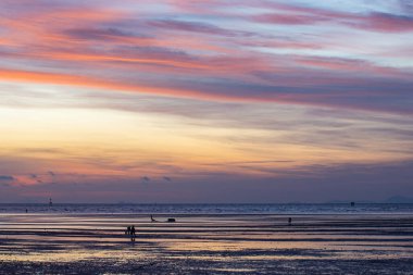Sakin sahil suyuna yansıyan renkli günbatımı gökyüzü