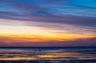 Durgun okyanus suyuna yansıyan renkli günbatımı gökyüzü