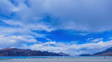 Sakin dağ gölünün üzerindeki geniş mavi gökyüzü