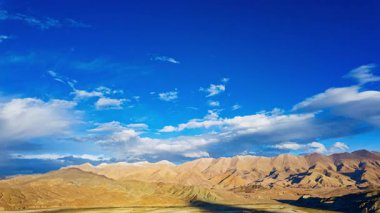 Altın dağ manzarasının üzerindeki parlak mavi gökyüzü