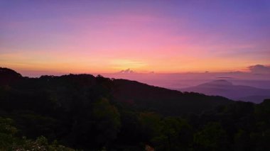 Karanlık dağ siluetinin üzerinde renkli günbatımı gökyüzü